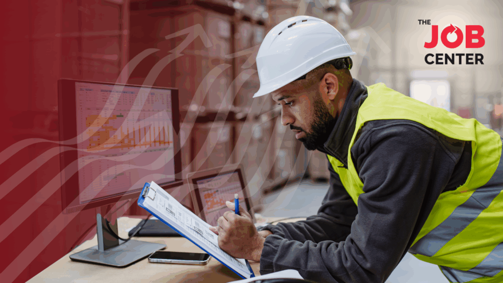 Night shift warehouse worker looks at a clipboard at a desk in the warehouse