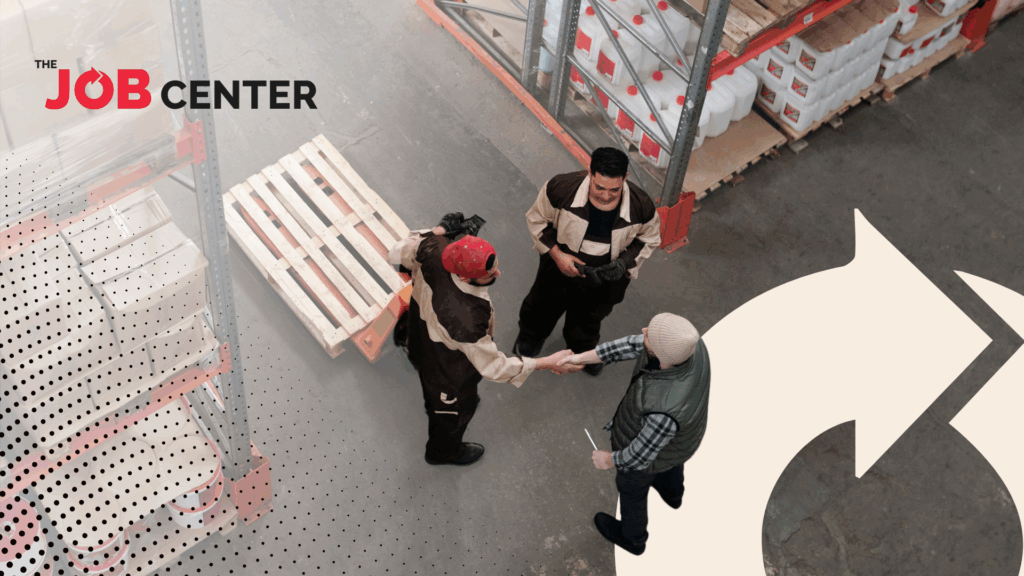Three warehouse workers stand in a circle, two shaking hands
